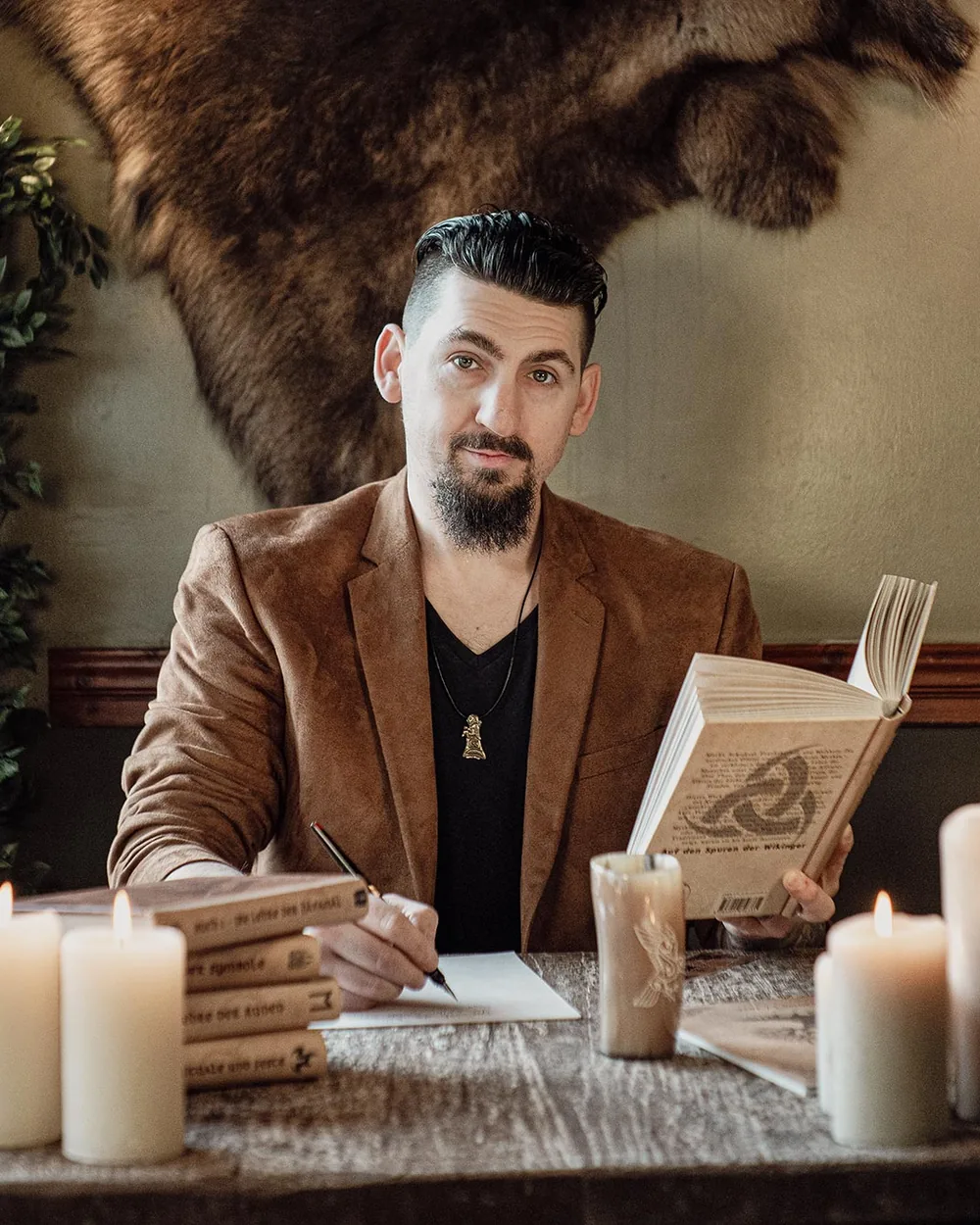 Alexander Ellmer am Tisch mit Büchern des Verlags NorseStory